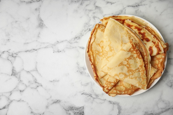 stack of fresh thin pancakes on white marble table top view space for - Блинчики с творогом, изюмом и сметаной