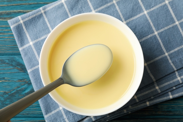 towel spoon and bowl with condensed milk on wooden background - Правила приготовления молочных супов