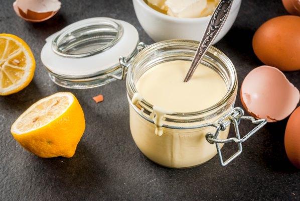 traditional basic sauces french cuisine hollandaise sauce in glass jar with ingredients for cooking eggs butter lemons on a black stone table - Голландский яично-масляный соус