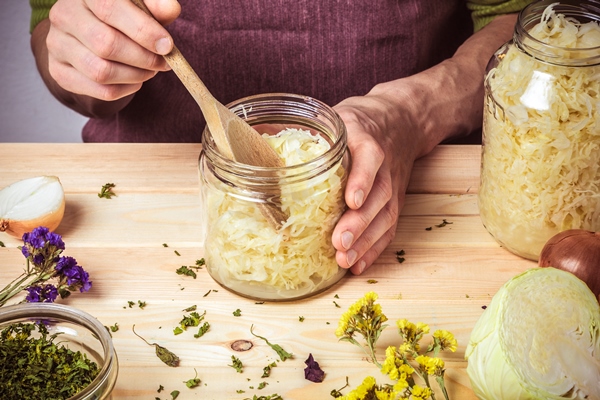 a bank of sauerkraut in the hands of a chef on the background of a table with ingredients - Монастырская кухня: овсянка с луком и изюмом, квашеная капуста