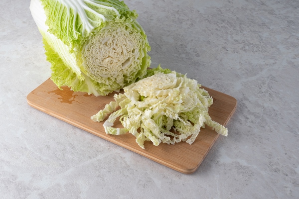 a fresh head of peking cabbage is chopped to make a salad marble background - Монастырская кухня: рыбный суп с кальмаром, запеканка с рыбой, салат овощной с винным уксусом