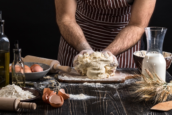 a handful of flour with egg on a rustic kitchen against the background of men s hands knead the dough ingredients for cooking flour products or dough bread muffins pie pizza dough copy space - Дрожжевое сдобное тесто