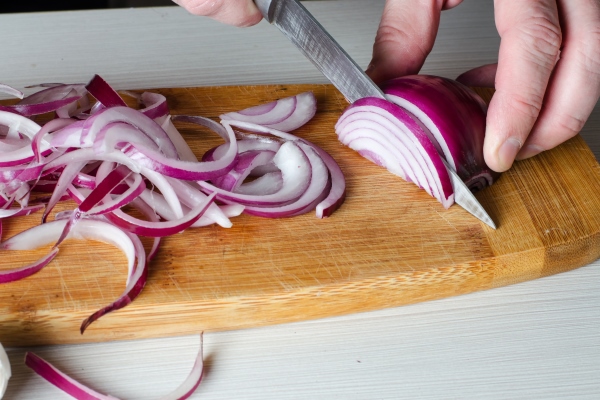 a man cuts red onions on a wooden chopping board - Монастырская кухня: суп-пюре морковно-тыквенный, овощи-гриль, салат из красной фасоли с грибами и сухарями