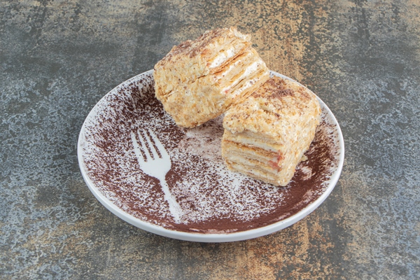 a white plate with two pieces of napoleon cake and cocoa powder - Монастырская кухня: архиерейская солянка, постный "Наполеон"