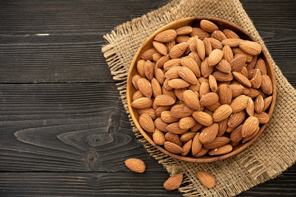almond in a wooden bowl on a wooden background near a bag from burlap healthy food and snack organic vegetarian food - Паста из кешью с уксусом и специями