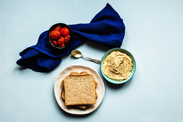baked tomatoes hummus and bread a deep blue towel and a spoon blue surface top view horizontal image - Урбеч закусочный из тыквенных семечек