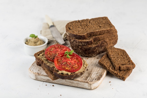 black bread sandwich with tomatoes and hummus on a wooden board - Монастырская кухня: перловая каша с овощами, паштет из фасоли