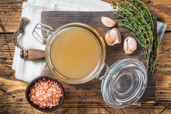 bone broth for chicken soup in a glass jar wooden background top view - Соус луковый острый