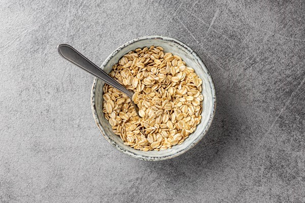 breakfast cereals uncooked oatmeal raw oat flakes in bowl top view - Овсянка с хурмой и тыквой без варки
