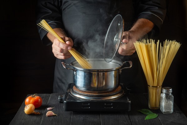 chef prepares italian pasta in saucepan with vegetables cook hands while cooking in restaurant - Лапша с поджаркой из овощей и сейтана (клейковины)
