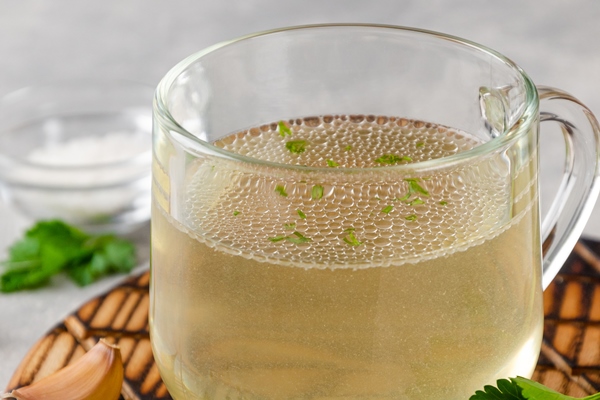 chicken broth in a glass cup with parsley garlic and other spices copy space - Ростбиф