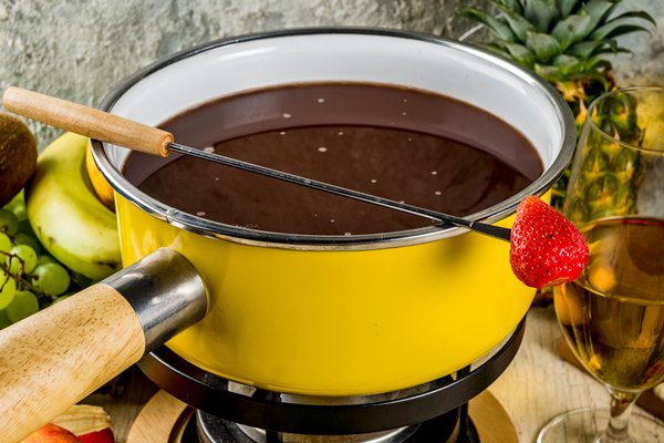 chocolate fondue in traditional fondue pot with forks white wine assorted various berries and fruit - Шоколадный соус