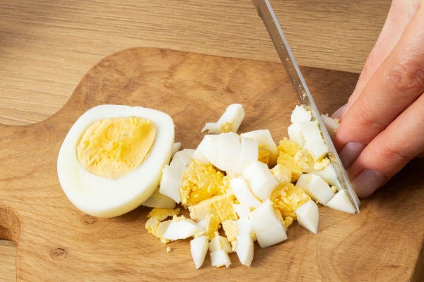 close up hand cutting eggs - Соус с каперсами