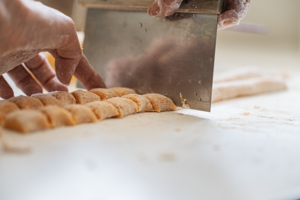 closeup view of female hands cutting fresh homemade pasta dough to make vegan gnocchi - Монастырская кухня: овощи в кляре, морковные клёцки