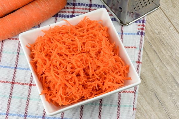 concept of preparing a healthy salad grated carrot in a white platter - Морковная бабка