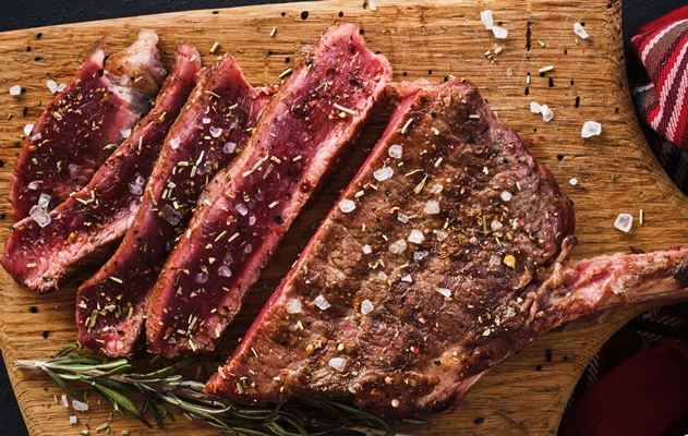 entrecote steak on the bone rib eye tomahawk steak on the on a cutting board with rosemary roasting rare - Разновидности блюд из жареного мяса