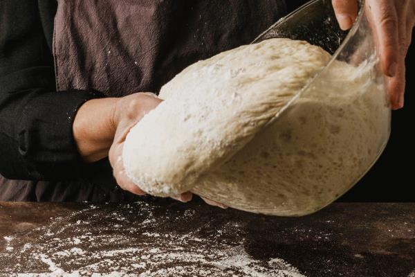 female chef pouring pizza dough on a table covered with flour - Монастырская кухня: чечевичный суп с квашеной капустой, жареные пирожки с капустой