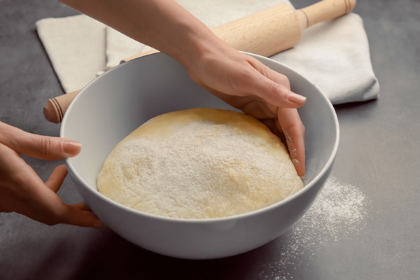 female chef with dough in bowl on kitchen table - Сладкий пирог из дрожжевого теста