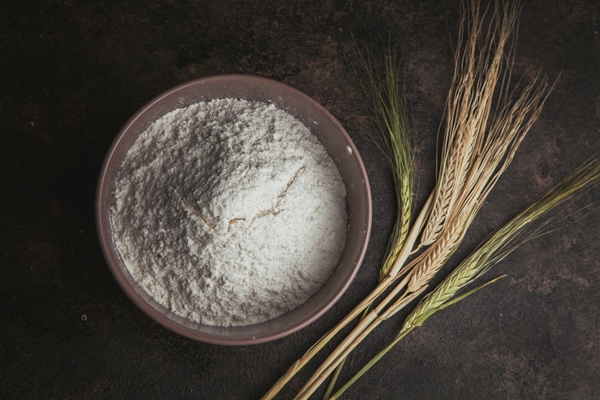 flour in a bowl with wheat flat lay on a dark brown - Картофельные блинчики с сыром