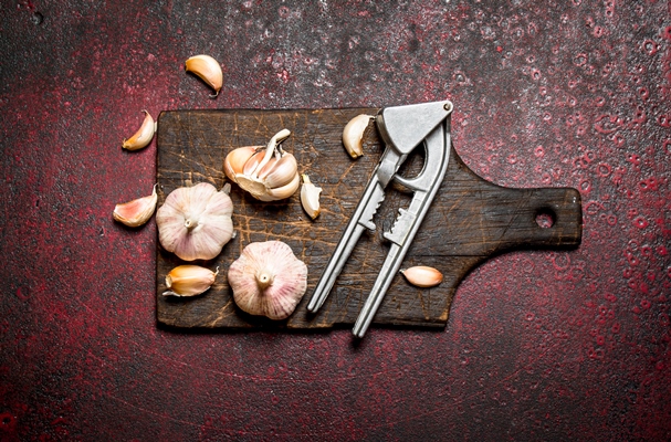 fragrant garlic with a press tool on a wooden board - Канапе с баклажанными рулетиками и постным паштетом