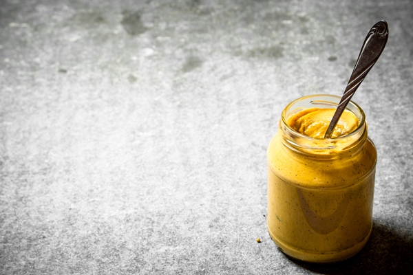 fresh mustard in a jar with a spoon on stone table - Шампиньоны в горчичном маринаде