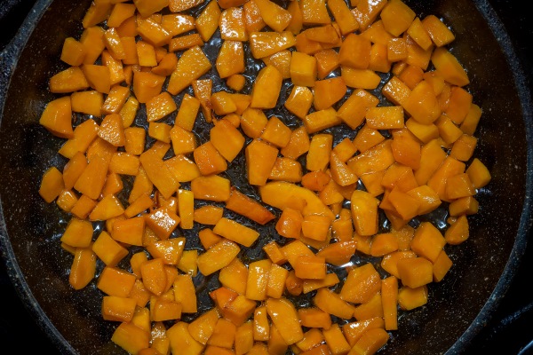 fried pumpkin cut into bars on a cast iron pan top view close up - Монастырская кухня: тыковник с черносливом и постные оладьи