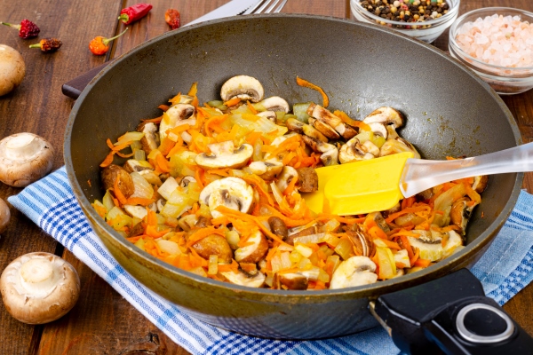 frying pan with fried mushrooms champignons onions and carrots on wooden table - Баклажаны, фаршированные грибами