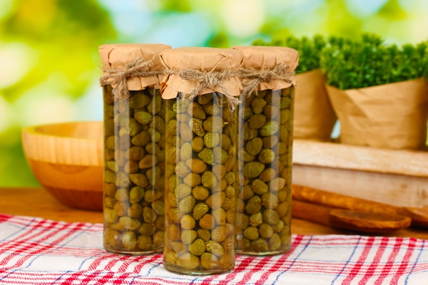 glass jars with tinned capers on green background - Соус винегрет