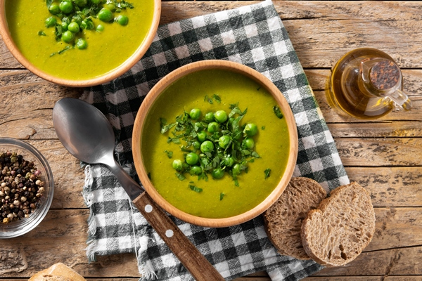 green pea soup in a bowl on rustic wooden table top view - Монастырская кухня: мидии в белом вине, салат из авокадо со спаржей и креветками