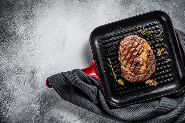 grilled rib eye ribeye steak in a pan gray background top view copy space - Лангет