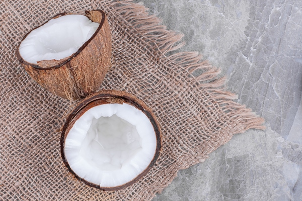 half cut of fresh healthy coconut placed on stone surface - Кокосовый урбеч с пряностями и специями