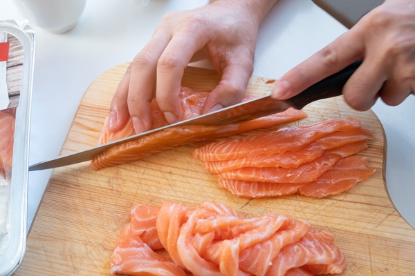 hand cook using knife slicing a fresh salmon on wooden chopping block - Монастырская кухня: архиерейская солянка, постный "Наполеон"