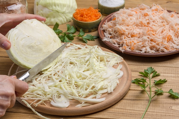 hands chop slice raw cabbage half cabbage head sauerkraut in plate homemade fermentation products close up - Монастырская кухня: луковый суп с капустой, свекольные котлеты