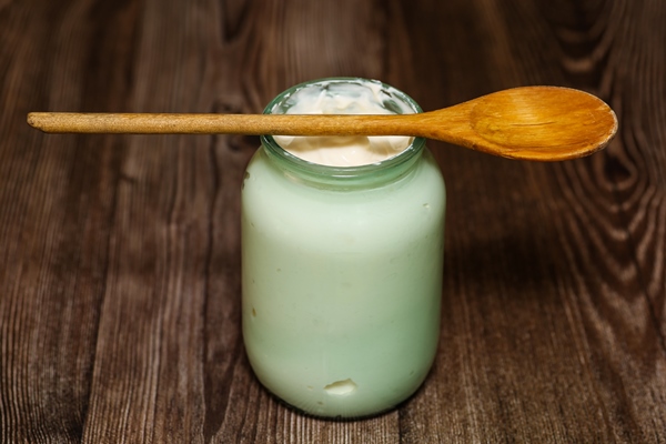 homemade milk sour cream in a glass jar with a rustic wooden spoon - Блинный торт со сметанным кремом
