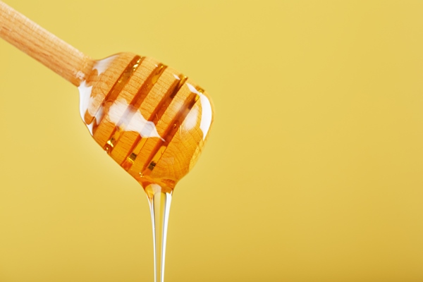 honey drips in a thin stream from a honey dipper on a yellow background - Монастырская кухня: печенье маковое с карамелью, морковный суп-пюре