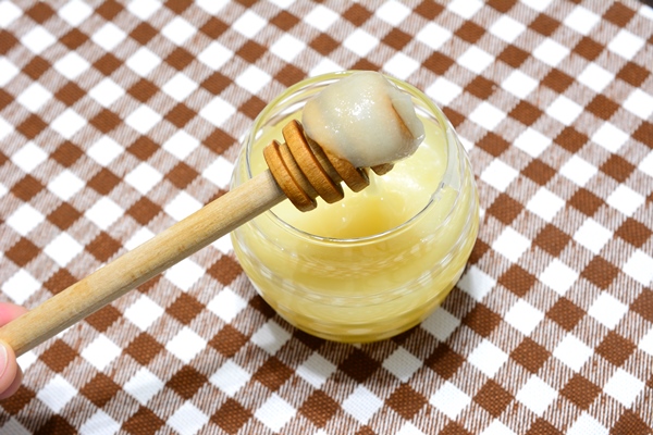 jar with linden honey and honey stick on plaid tablecloth close up - Льняной урбеч
