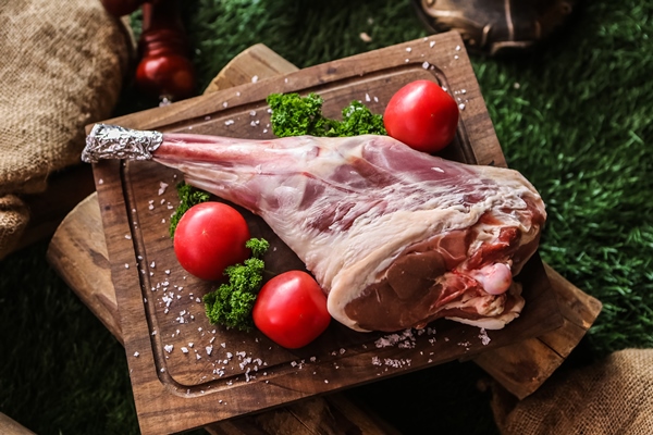lamb leg on the wooden board prepared for cook tomato broccoli salt top view - Баранина, запечённая в духовке