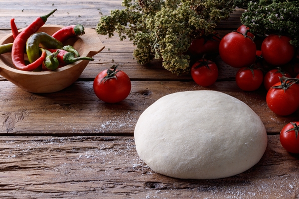 lump of dough on a wooden table surrounded with tomatoes and pepper - Сейтан (клейковина)