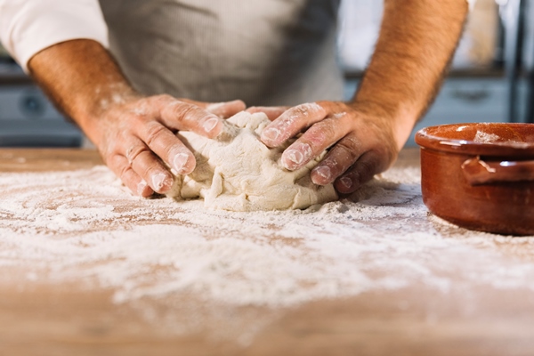 male baker kneading dough flour on wooden table - Монастырская кухня: перловка с квашеной капустой и яблочный рулет