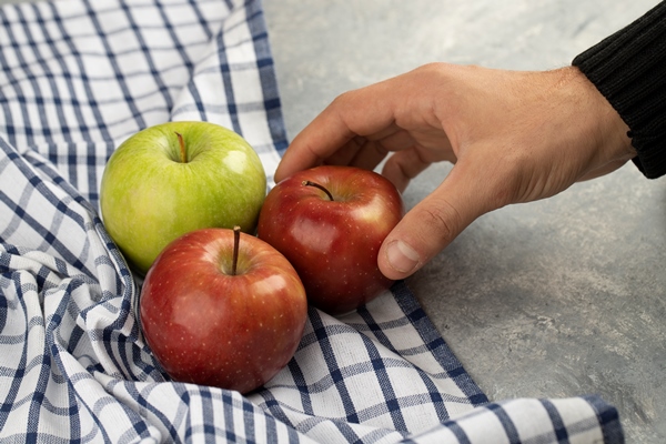 male hand taking fresh red apple from marble - Монастырская кухня: жареная зубатка, запечённое яблоко с орехами