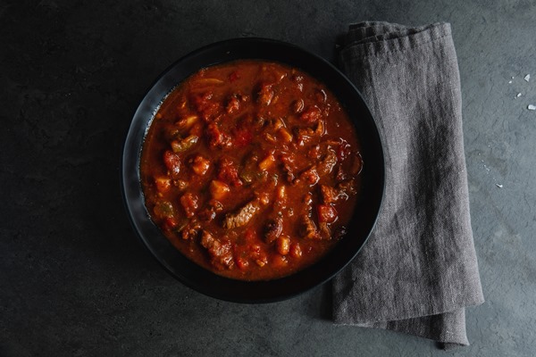 meat and vegetable stew served in dark bowl on grey background - Почки с грибами в винном соусе