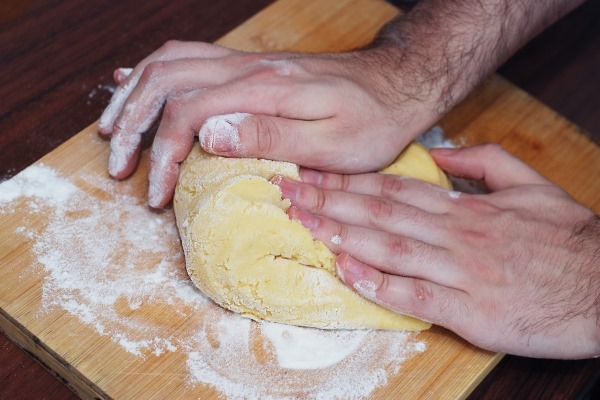 mens hands kneading bread dough on a cutting board - Монастырская кухня: лапша с грибами и лимонный пирог