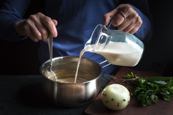 milk from the jug is poured into a base sauce for making bechamel - Блинчатый пирог с грибами