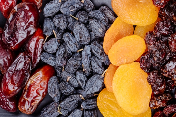 mix of dried fruits dates black raisins apricots and cherries on black background top view - Перловка без варки