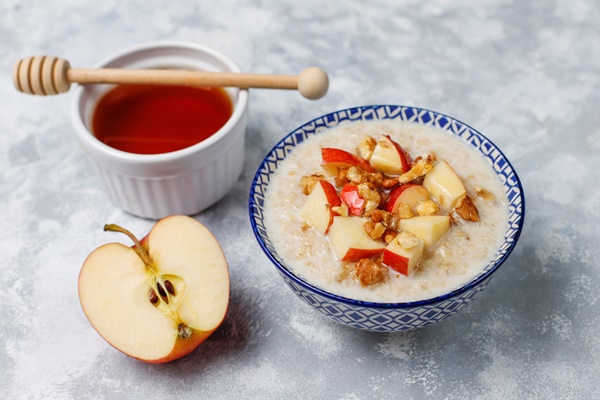 oatmeal porridge in a bowl with honey and red apple slices top view - Овсянка с яблоком и корицей