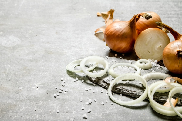 onion cut into rings on a stone stand on grey table - Монастырская кухня: мидии в белом вине, салат из авокадо со спаржей и креветками