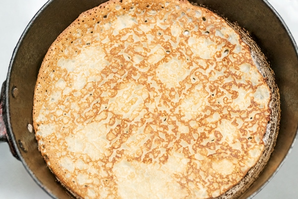 pancake fried in a cast iron pan close up top view - Блинцы на ряженке