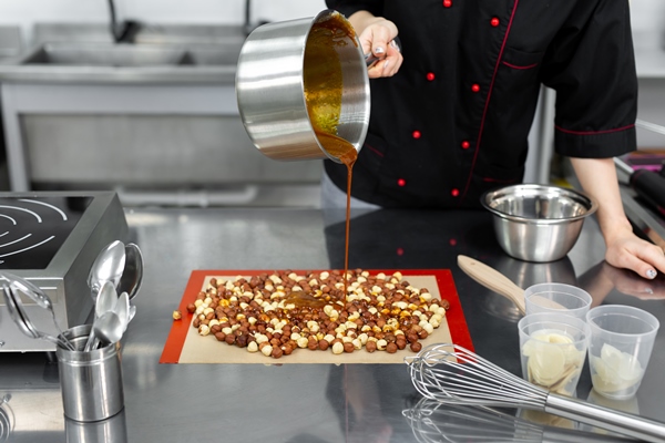 pastry chef pours hot syrup caramel on hazelnuts to make praline 1 - Ореховая паста из фундука