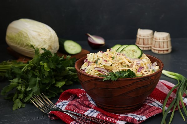 peking cabbage cucumber red onion and cheese salad in a bowl against a dark surface - Монастырская кухня: рыбный суп с кальмаром, запеканка с рыбой, салат овощной с винным уксусом