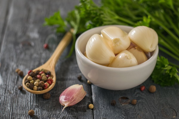 pepper in a wooden spoon and peeled garlic in a bowl on a wooden table healthy natural seasoning component of traditional medicine - Монастырская кухня: чесночная похлёбка, медовые рогалики